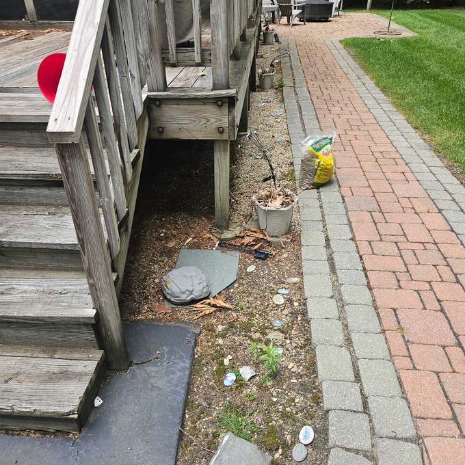 Gravel strip beside a deck with scattered debris before work