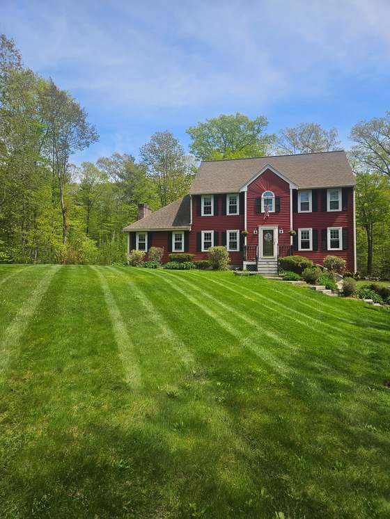 Freshly striped lawn in front of a red colonial home